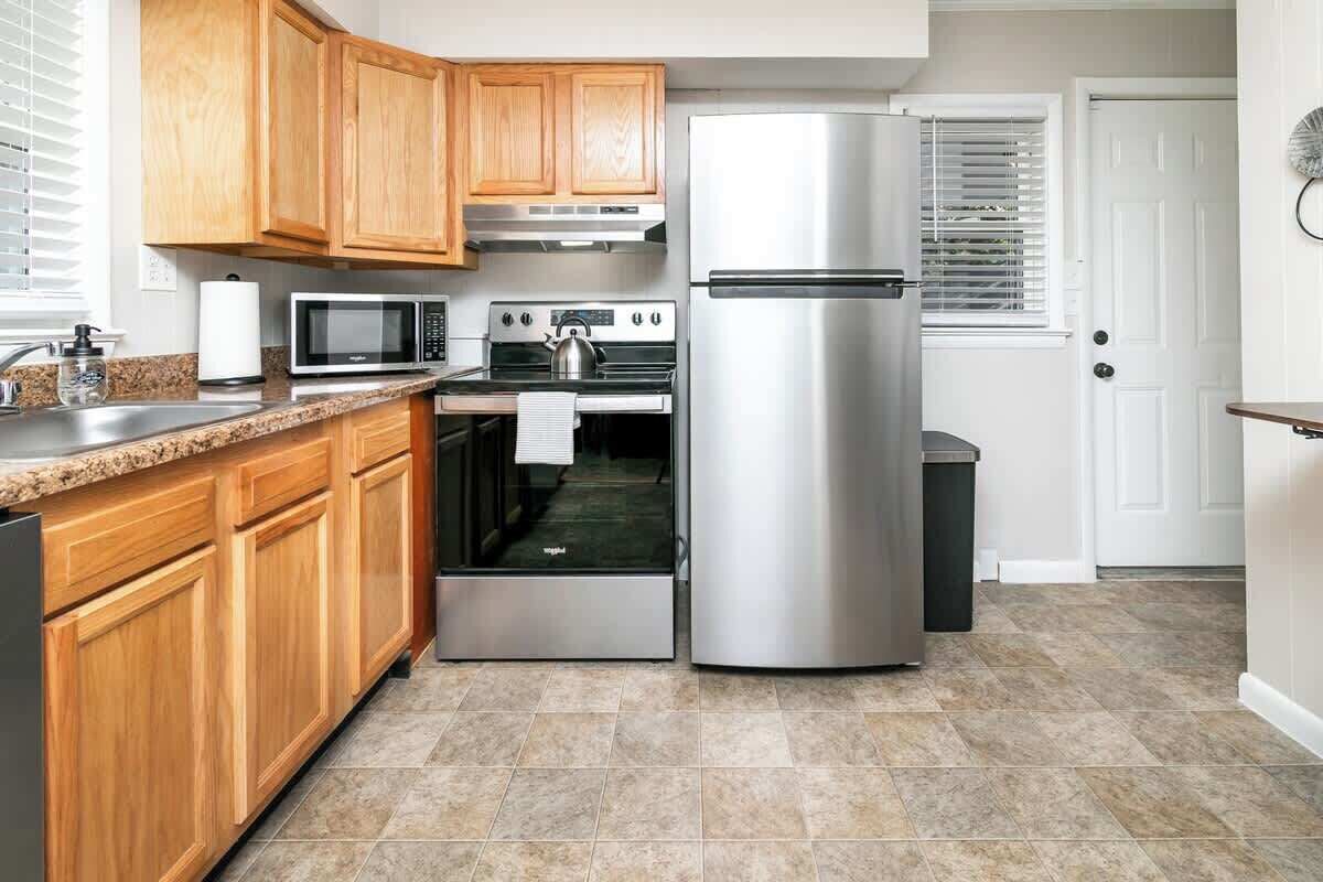 A kitchen with wooden cabinets, a stainless steel refrigerator, a microwave, and an oven.
