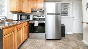 A kitchen with wooden cabinets, a stainless steel refrigerator, a microwave, and an oven.