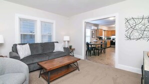 A living room with a grey sofa, a wooden coffee table, and a dining area with a table and chairs. - Salisbury Hideaway (Salisbury)