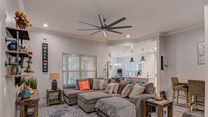 Un salon moderne avec un canapé d’angle, un ventilateur de plafond et un panneau décoratif accueillant.
