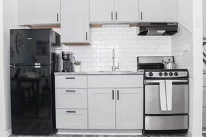 A kitchen with white cabinets, a black refrigerator, a coffee maker, and a stove. - 5 min walk to the ocean I Downtown | Ocean view (Myrtle Beach)