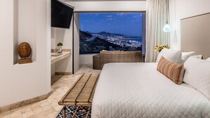 Una habitación de hotel moderna con una cama grande, televisión, vista a la ciudad y ventilador de techo.