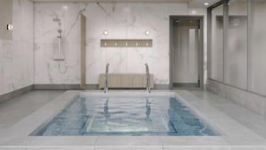 En modern inomhuspool med en vägg av marmor och en bänk.