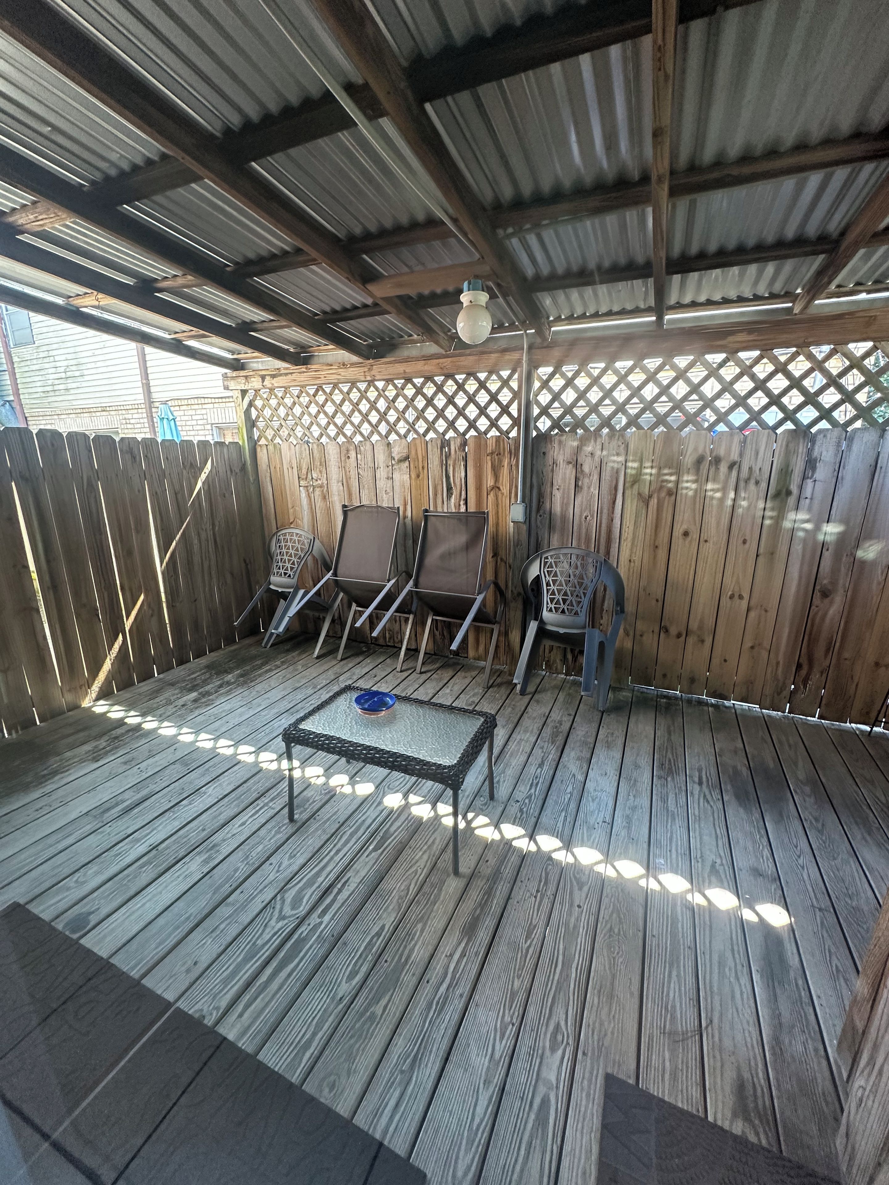 An outdoor patio with wooden flooring, a metal table, and four chairs.