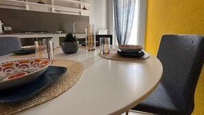 Comedor con mesa redonda, sillas y cocina al fondo.