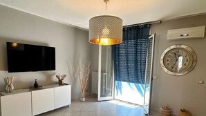 Una sala de estar moderna con un televisor de pantalla plana, un jarrón decorativo, un tapete estampado, un reloj redondo y una lámpara en el techo.