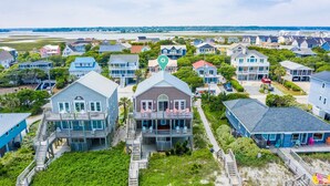 A coastal residential area with multiple houses, including a prominent two-story house with a balcony and a deck. - Hot Tub, BeachFront, Private, Hammocks on the Beach (Surf City)