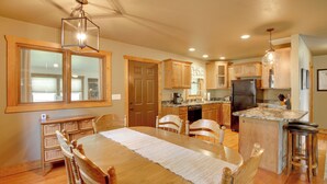 A spacious kitchen with wooden cabinets, a granite countertop, and a central island with stools. - Cozy Lead Cabin w/ Deck < 1 Mi to Ski Slopes! (Lead)