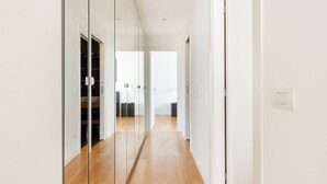 A hallway with a glass partition, wooden flooring, and a view into a room with a bed and a desk. - GuestHost - Bright, brand new Apartment- Milano Centrale (Milano)