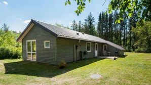 Ein eingeschossiges Haus mit Satteldach, einer Veranda und einer kleinen Terrassenfläche.