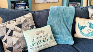 Un salon avec un canapé bleu foncé, des coussins décoratifs et une bibliothèque contenant divers objets.