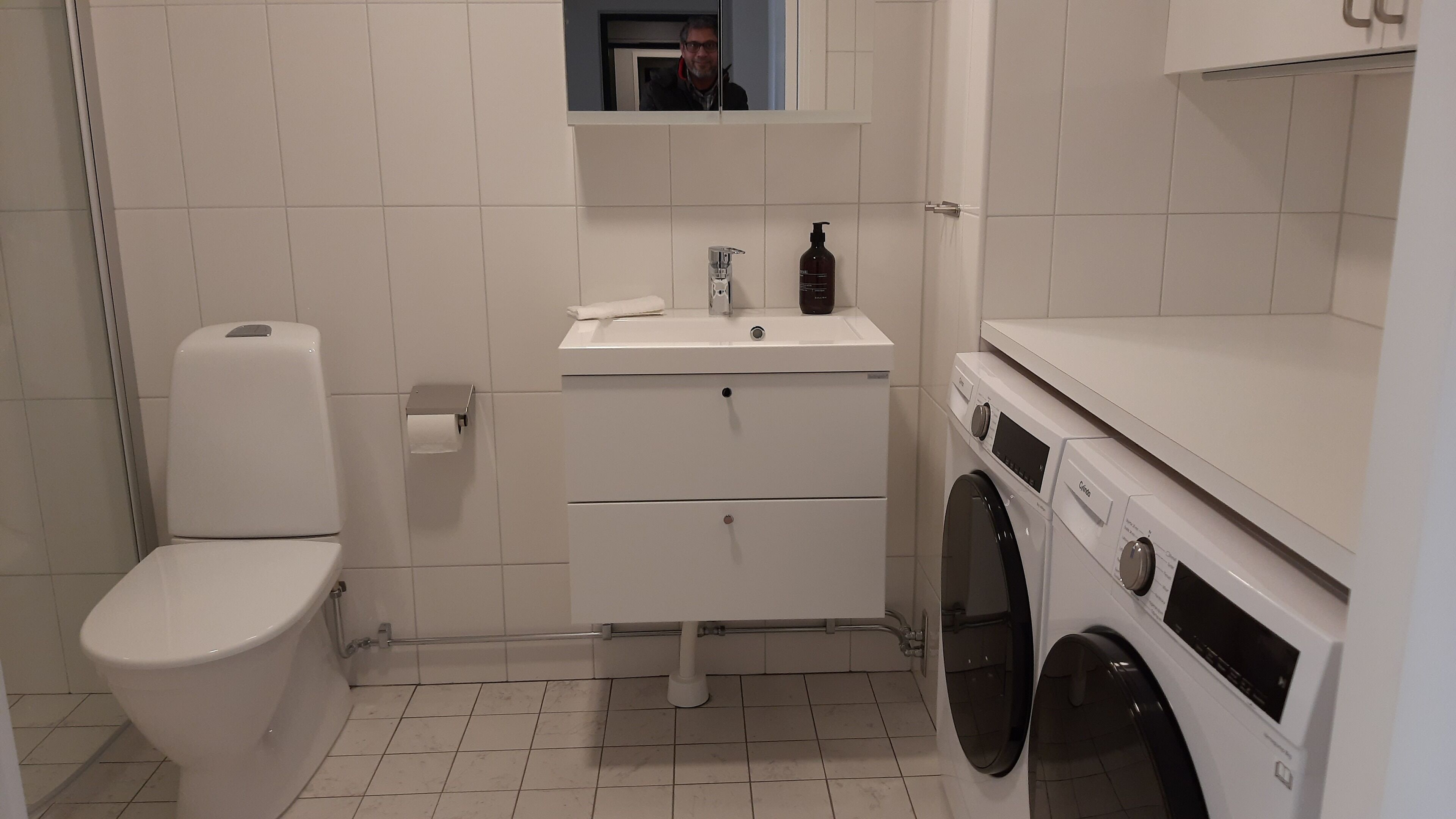 A small, clean bathroom with a toilet, sink, and washing machine.