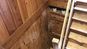 A wooden staircase with a handrail, wooden walls, and a small shelf with a plant.
