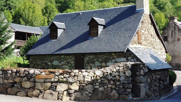 A stone house with a sloped roof and two small dormer windows.