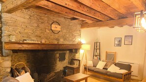 A cozy living room with a stone fireplace, wooden furniture, and a clock on the wall.