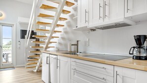 Une cuisine moderne avec des meubles blancs, un plan de travail en bois, un lave-vaisselle encastré et une machine à café.
