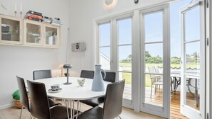 Un coin repas avec une table ronde, des chaises noires et un buffet blanc doté de portes en verre.