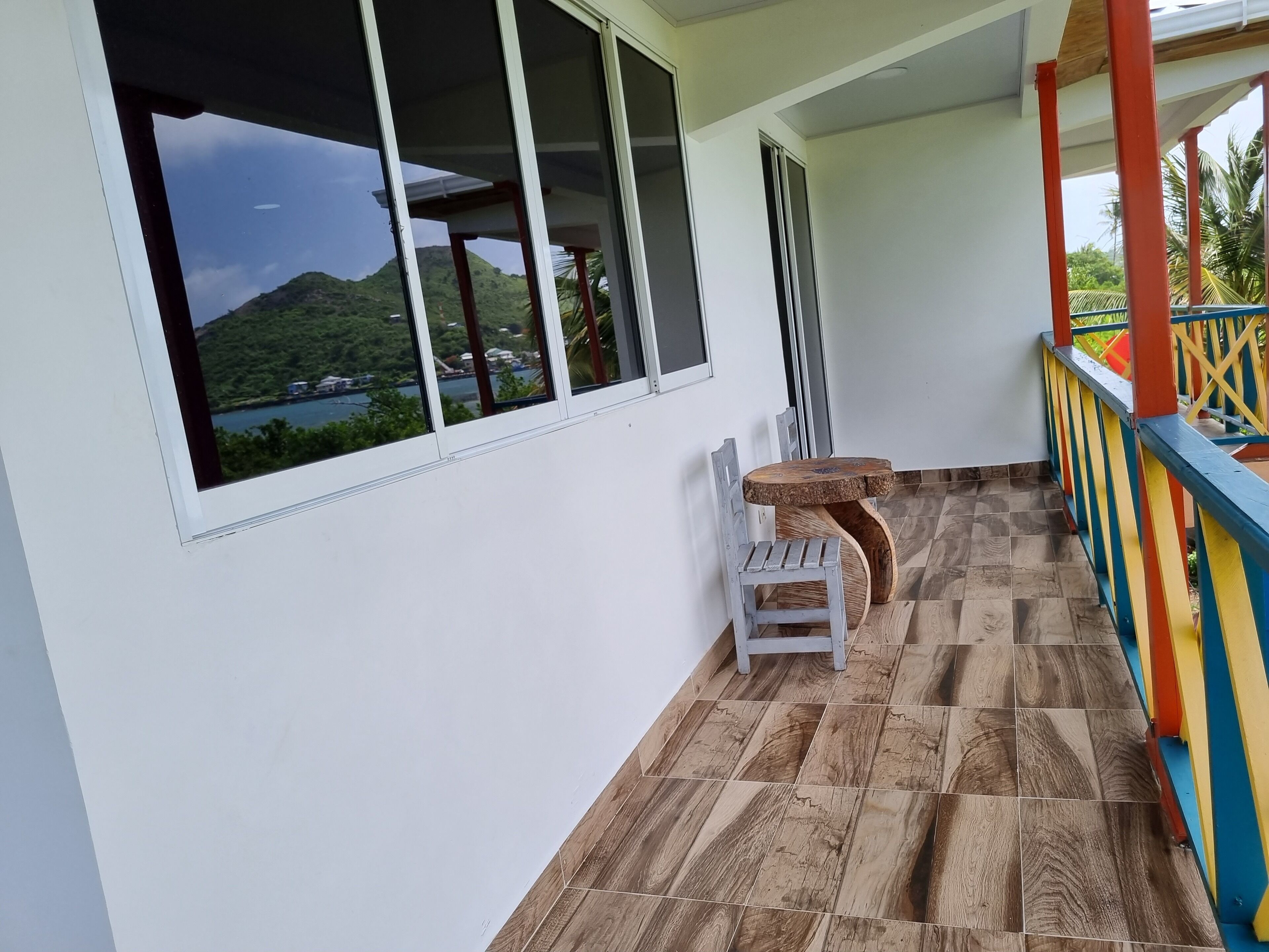 A balcony with a wooden floor, a white chair, and a small table.