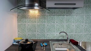 Et køkken med komfur, vask og et mønstret backsplash.