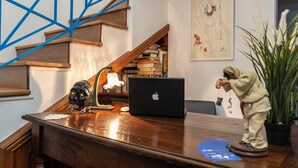 Et træskrivebord med en bærbar computer, en skrivebordslampe og en figur.