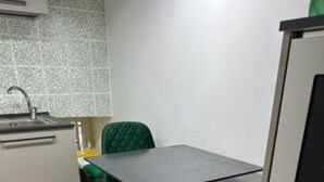 A small kitchenette with a sink, a stove, and a countertop. There is a table with two chairs and a cabinet to the right. - Two rooms chiaia 37  (Napoli)