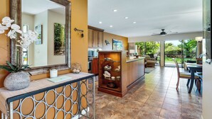 A modern kitchen with a wooden countertop, a large mirror, and a decorative shelf. - Fully Loaded 1 Bedroom 2 Bathroom Condo in Kihei, Maui!  (Kihei)