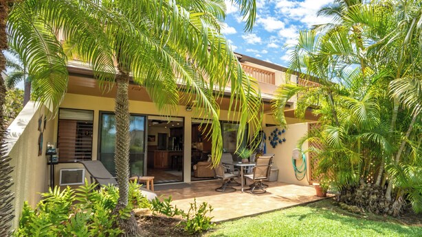 A house with a patio, outdoor seating, and a garden with palm trees. - Fully Loaded 1 Bedroom 2 Bathroom Condo in Kihei, Maui!  (Kihei)