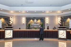 A reception area with a 'Hilton Grand Vacations Club' sign, a reception desk, and two decorative wall sconces. - Las Vegas | Pool & Strip Access | Urban Comfort Stay (Las Vegas)