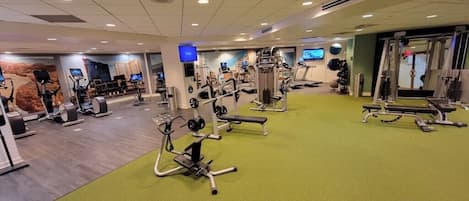 A gym with various exercise equipment, including treadmills, stationary bikes, and weight machines.