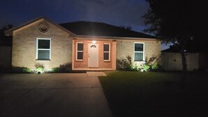 A two-story house with a front porch, a visible door, and two windows. - Cozy Home on RGV (Alton)