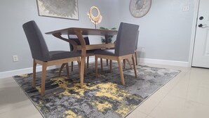 A dining area with a round table and four chairs, a patterned rug, and a wall clock. - Cozy Home on RGV (Alton)
