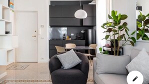 A modern living room with a grey sofa, a black armchair, and a dining area with a round table. - Gemelli Cozy quiet Home- well connected (Roma)