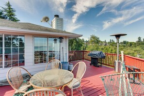 Eine überdachte Terrasse mit Tisch, Stühlen, einem Grill und einer Laterne.