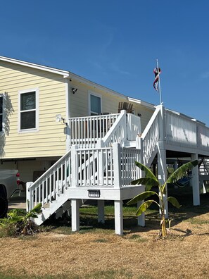 A two-story house with a white deck and a flagpole.