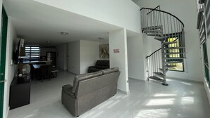 A spacious living area with a modern staircase, a leather sofa, and a dining area.