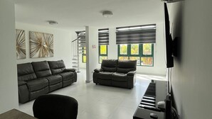 A modern living room with a sofa, a dining table, and a television.