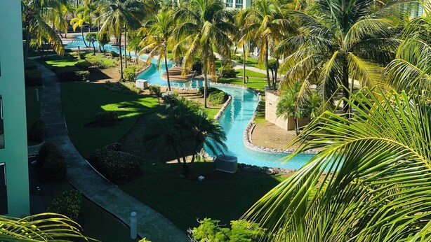 A resort with a pool area, palm trees, and buildings with a consistent architectural style.