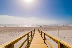 A wooden boardwalk leading to a beach with a clear sky and calm sea. - SPACIOUS CONDO BY THE BEACH! 
Beautiful lagoon views and close to restaurants! (Orange Beach)