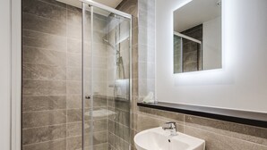 A modern bathroom with a glass-enclosed shower, a white sink, and a mirror above it. - GuestReady - Hideaway in Vauxhall (Liverpool)