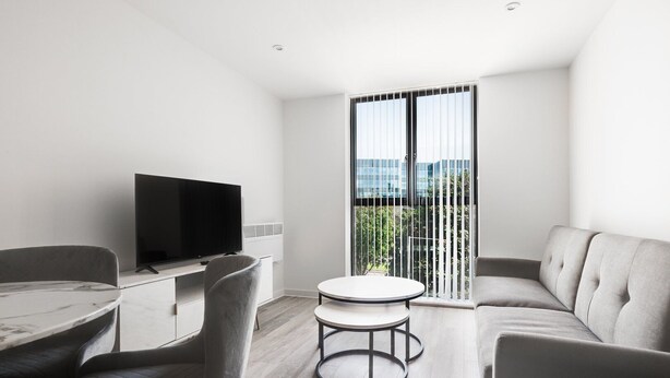 A modern living room with a flat-screen TV, a round table, and a sofa. - GuestReady - Hideaway in Vauxhall (Liverpool)