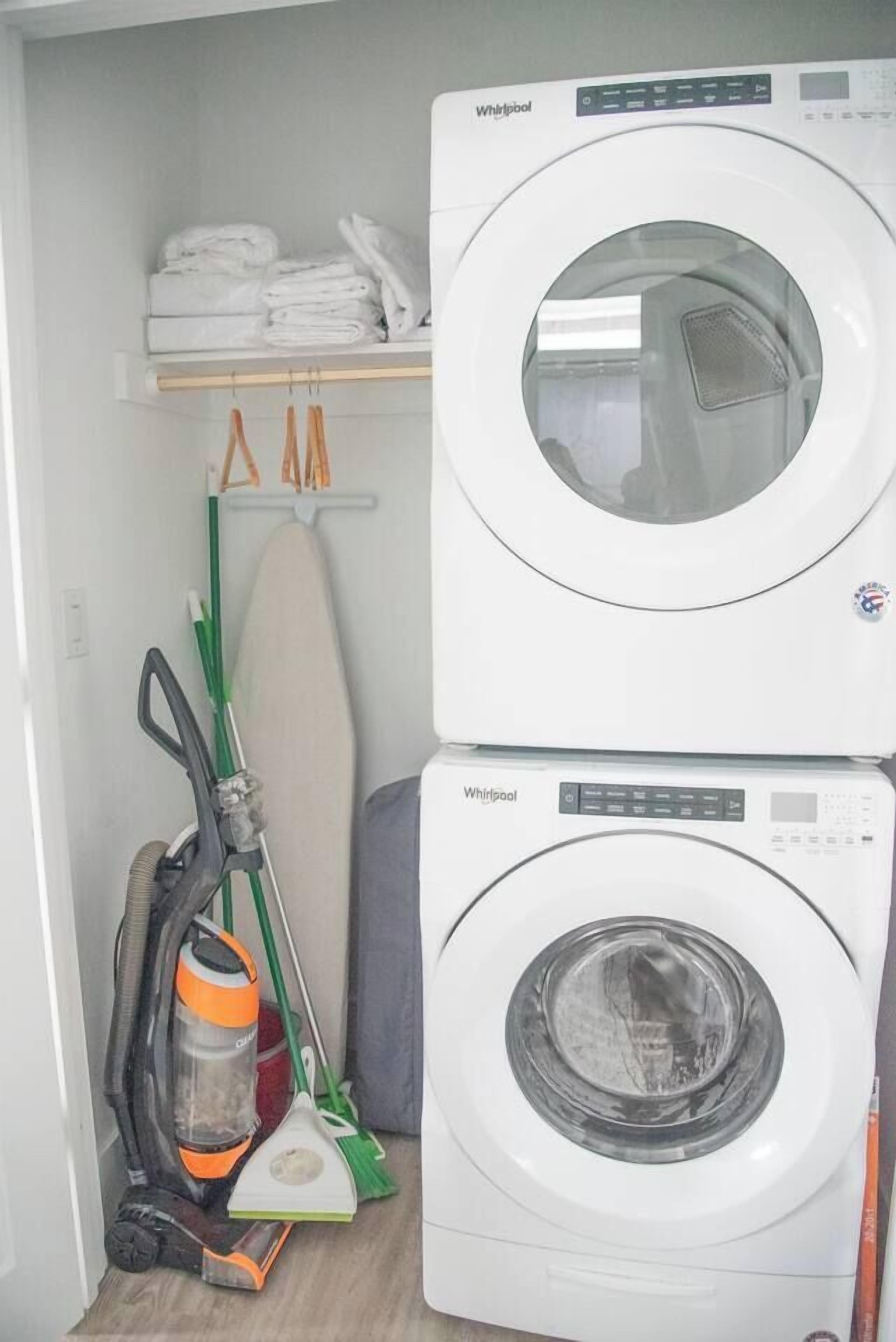 A laundry room with stacked washing machines and a vacuum cleaner.
