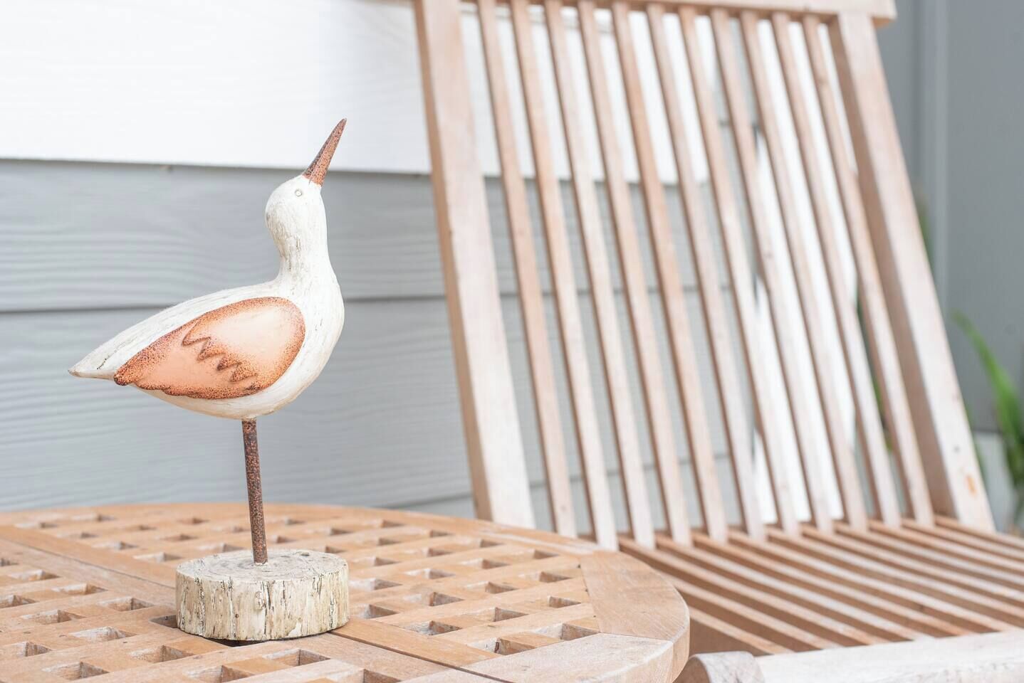 Una silla de madera con listones verticales y una base de mesa de ratán trenzado.