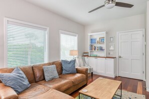 A living room with a brown leather sofa, a wooden coffee table, and a ceiling fan.
