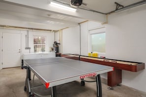 Une pièce équipée d’une table de ping-pong, d’un billard et d’une fenêtre avec des stores.