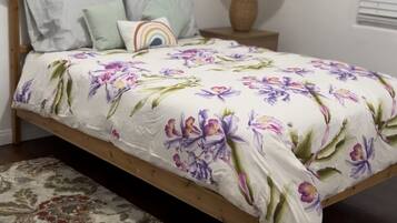 Una cama con colcha estampada, una lámpara de noche y una alfombra con motivos.