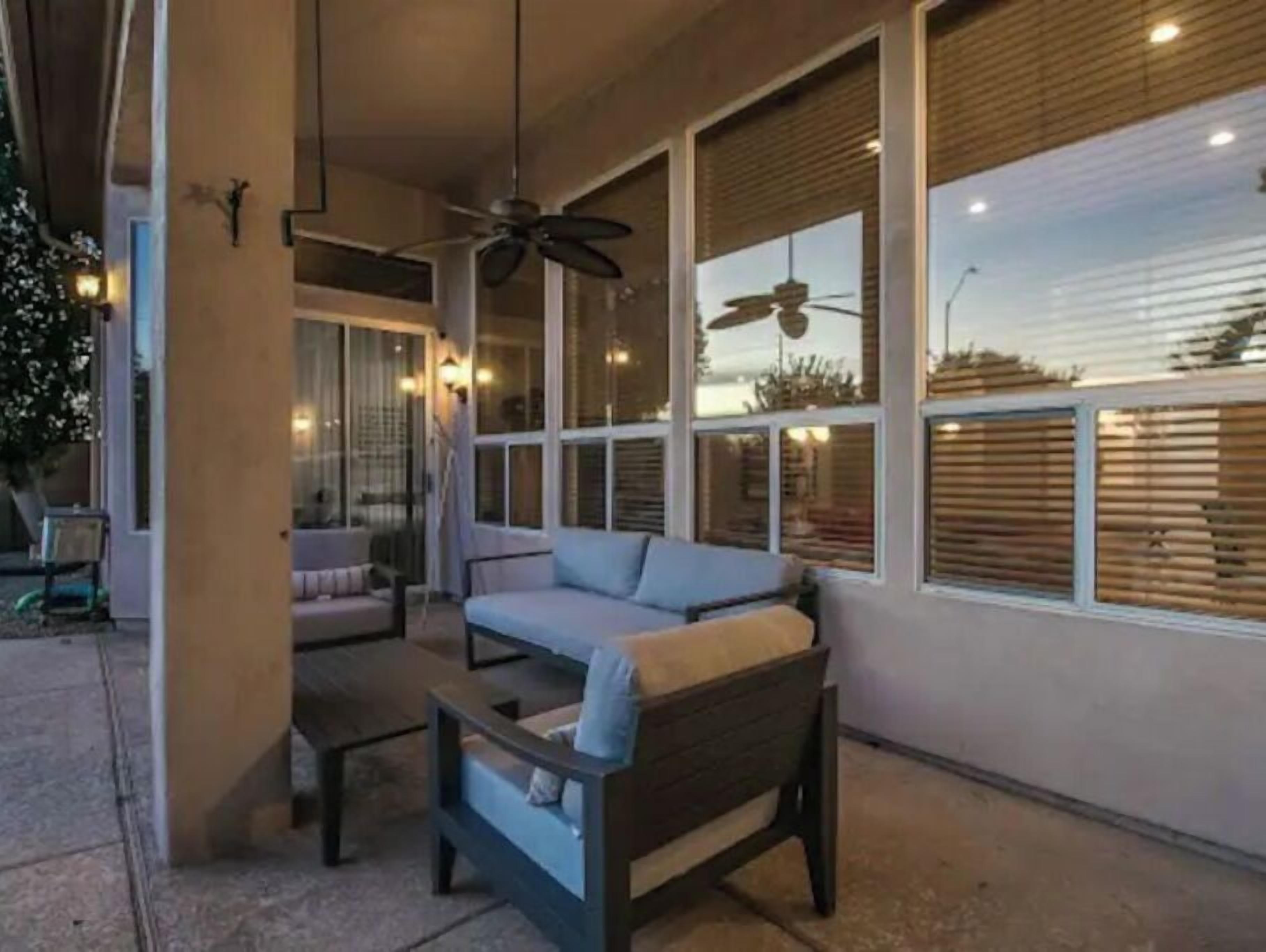 A covered outdoor seating area with a sofa, a table, and a ceiling fan.