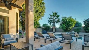 Een terras buiten met lounge stoelen en een plafondventilator.