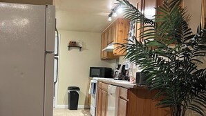A kitchen with wooden cabinets, a refrigerator, a microwave, and a sink. - Sled Dog Cabin: Family, Pet Friendly Quiet Home in Wasilla (Wasilla)
