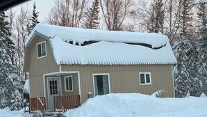 A two-story house with a snow-covered roof and a wooden porch. - Sled Dog Cabin: Family, Pet Friendly Quiet Home in Wasilla (Wasilla)