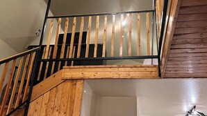 A wooden staircase with a metal railing leading to an upper floor. - Sled Dog Cabin: Family, Pet Friendly Quiet Home in Wasilla (Wasilla)